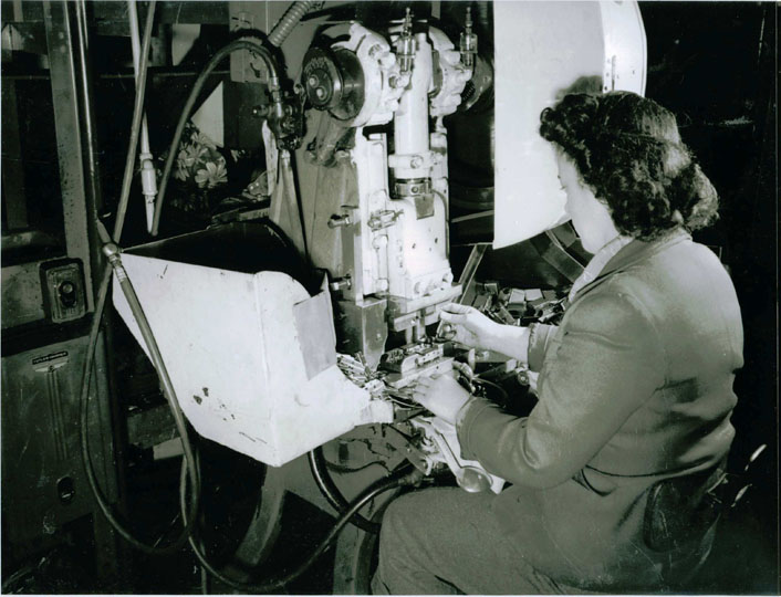 Woman sitting at machine assembling die spacers and clips